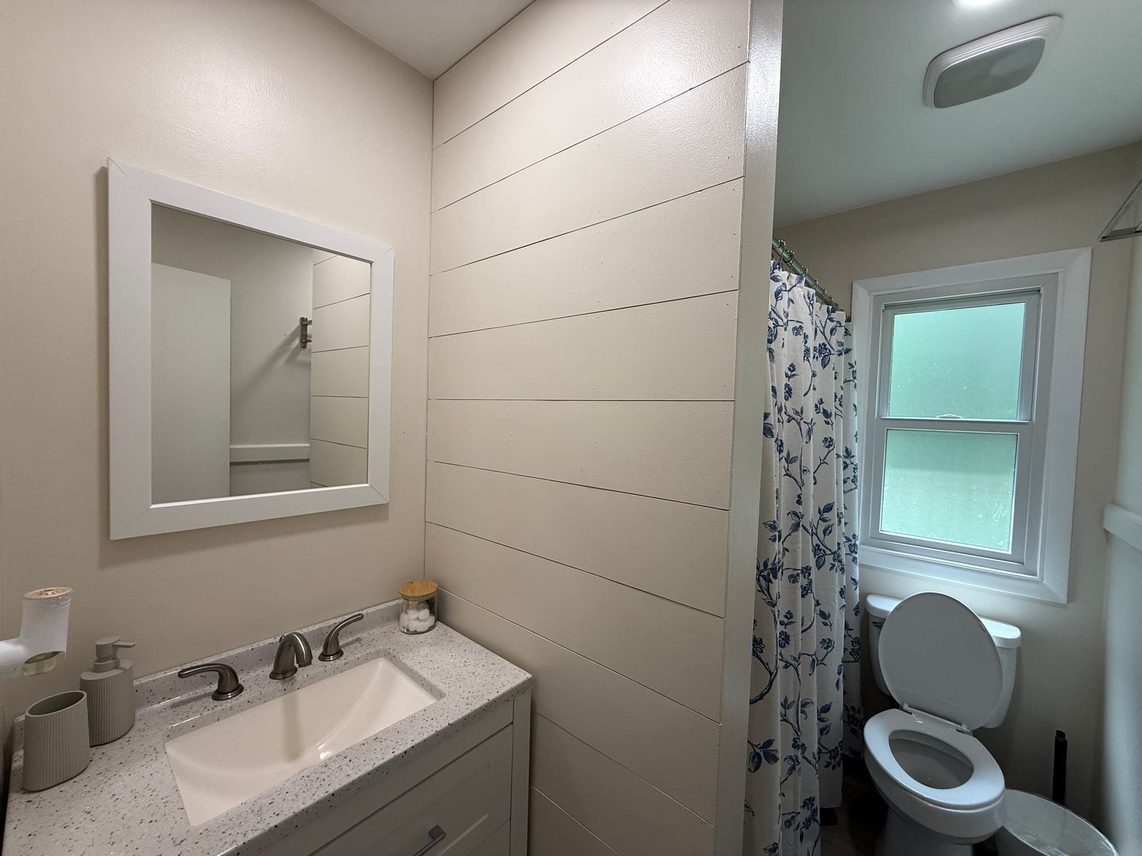 Full bathroom with a vanity, shiplap wall, and tub-shower