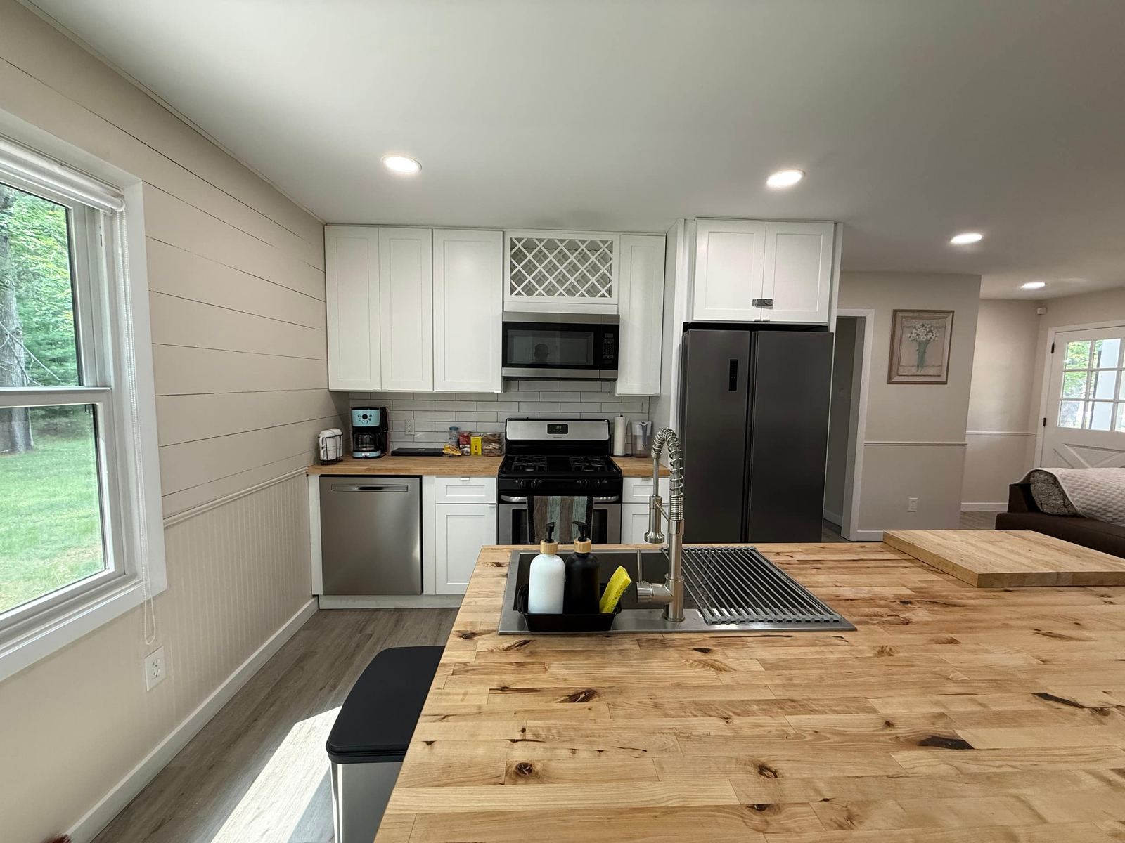 Kitchen with white shaker cabinets, subway tile, gas range, and a butcher-block island