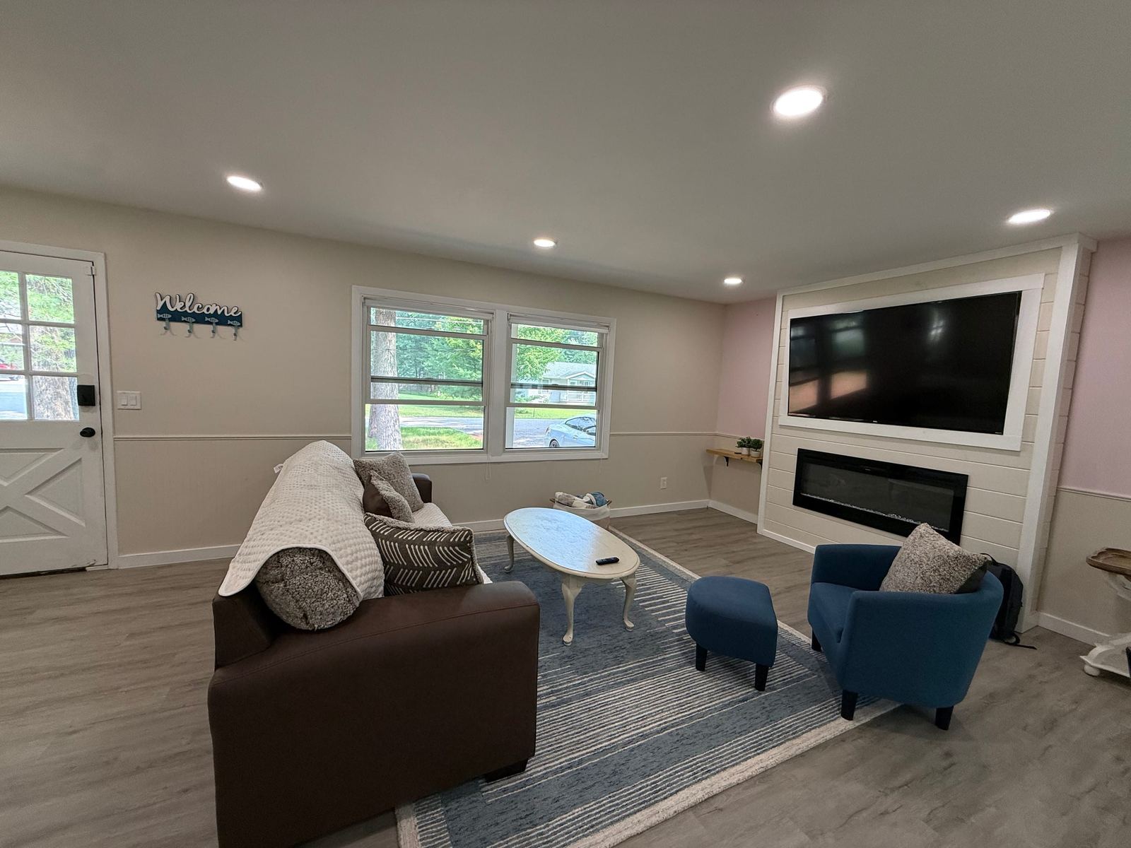 Living room with a sofa, blue armchair, and an electric fireplace below the TV
